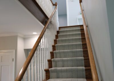 A staircase with a carpeted staircase and a wooden railing