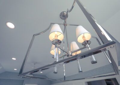 A chandelier with white shades is hanging from the ceiling in a room.