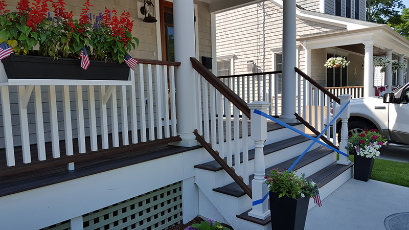 A white truck is parked in front of a white house with a porch and stairs.