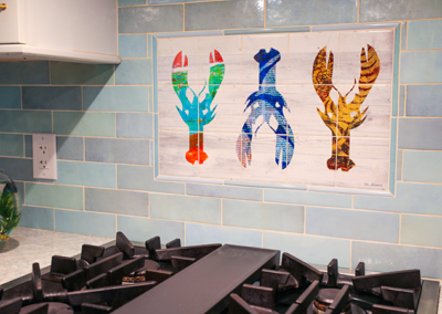 A painting of lobsters hangs above a stove in a kitchen.