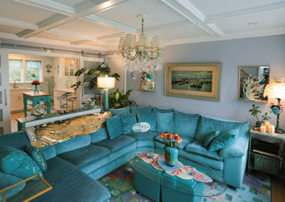 A living room with a blue sectional couch and a chandelier