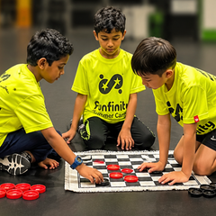 Three children in neon shirts play checkers on the floor, focusing on red and black pieces.
