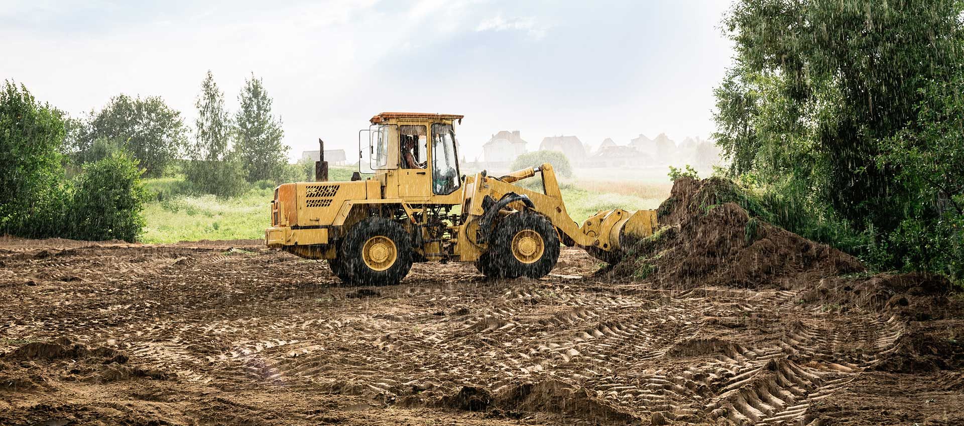 large yellow wheel loader aligns a piece of land