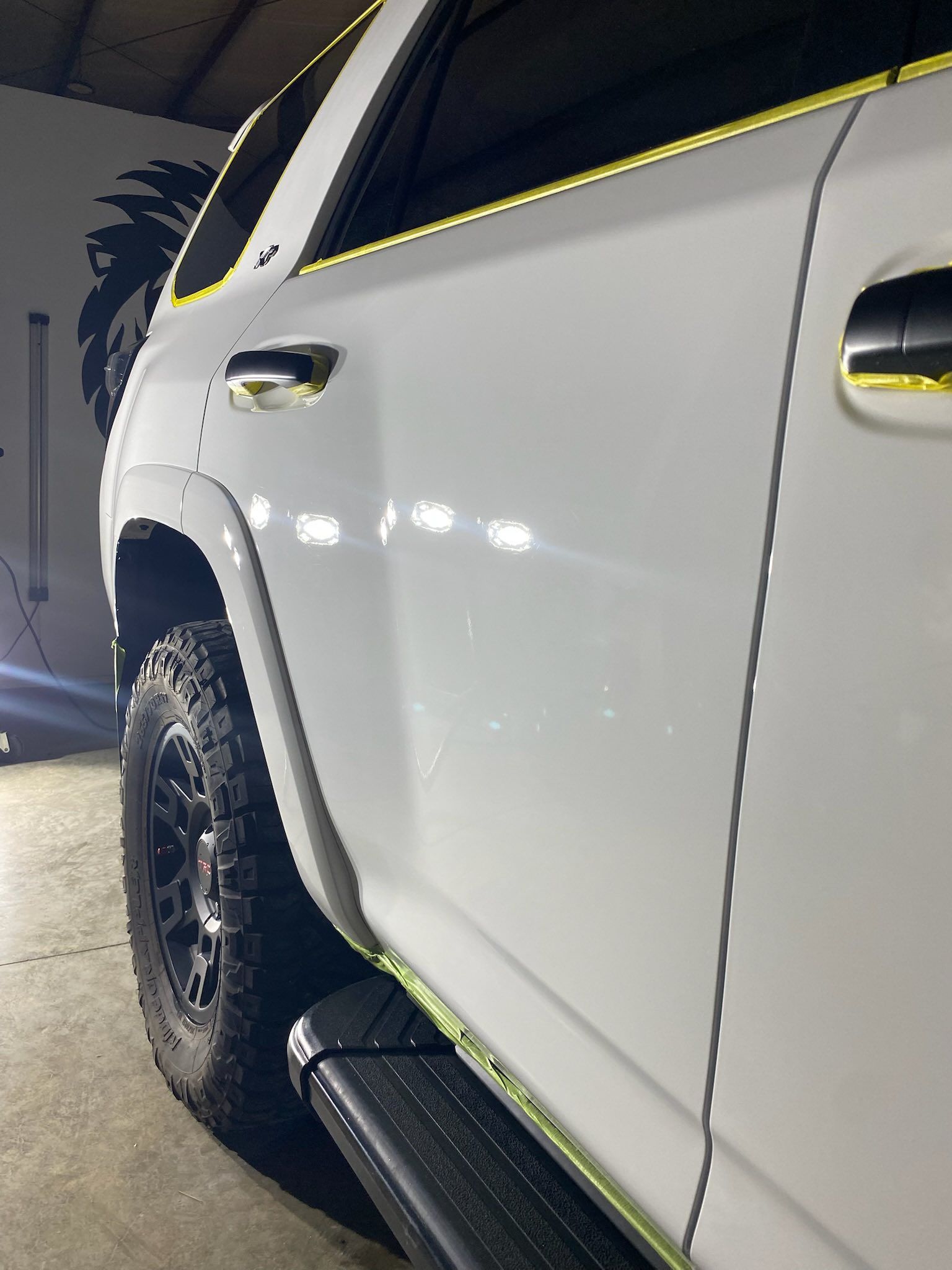 A white suv with black wheels is parked in a garage.