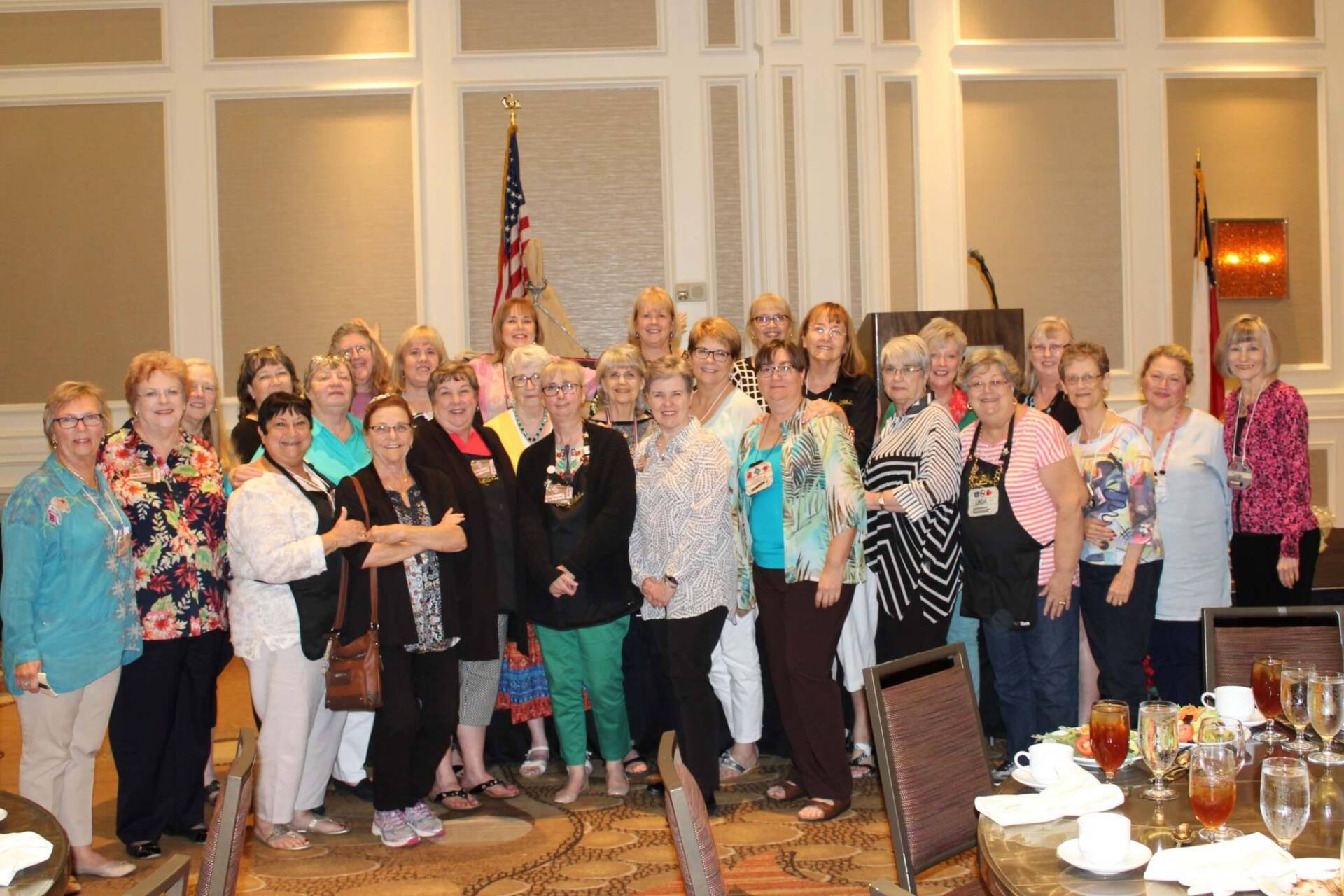 A group of people standing together for a photo in a conference room with a flag in the background.
