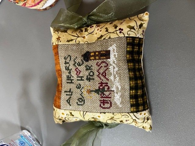 A decorative fabric Christmas pillow with embroidered text reading 