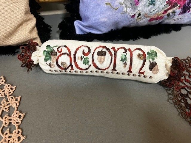 A cylindrical fabric cushion embroidered with the word 
