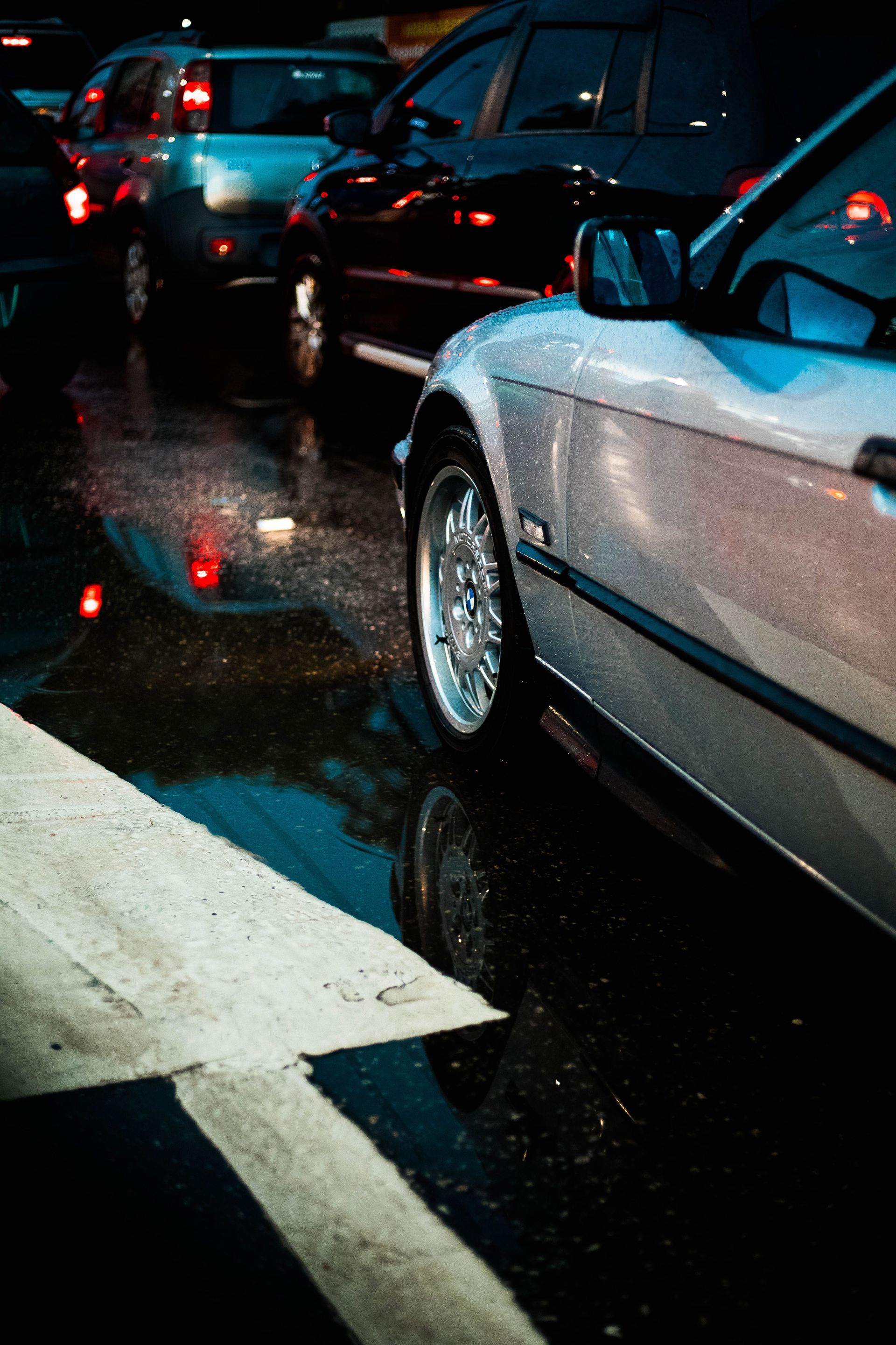Wet city traffic at night with cars stopped in rain, reflections on the road