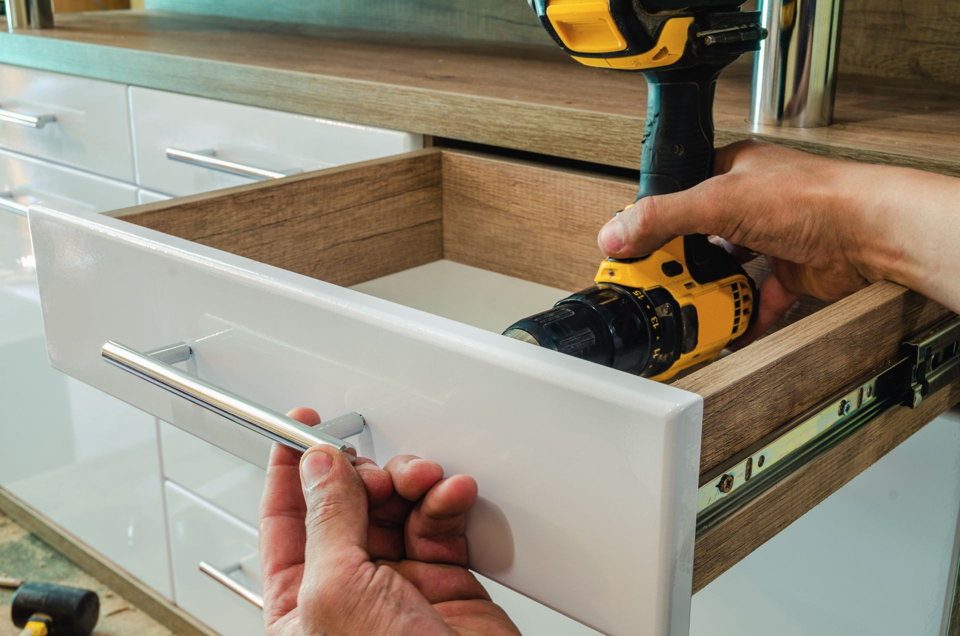 A person is holding a drill in a drawer.