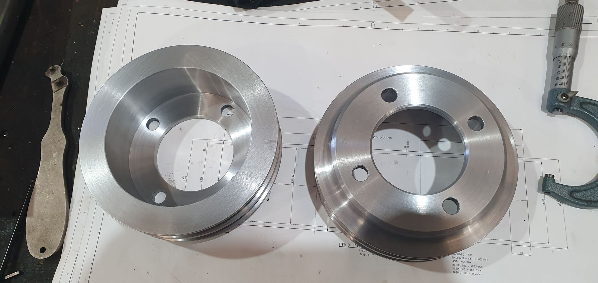Two metal wheels are sitting on a table next to a wrench.