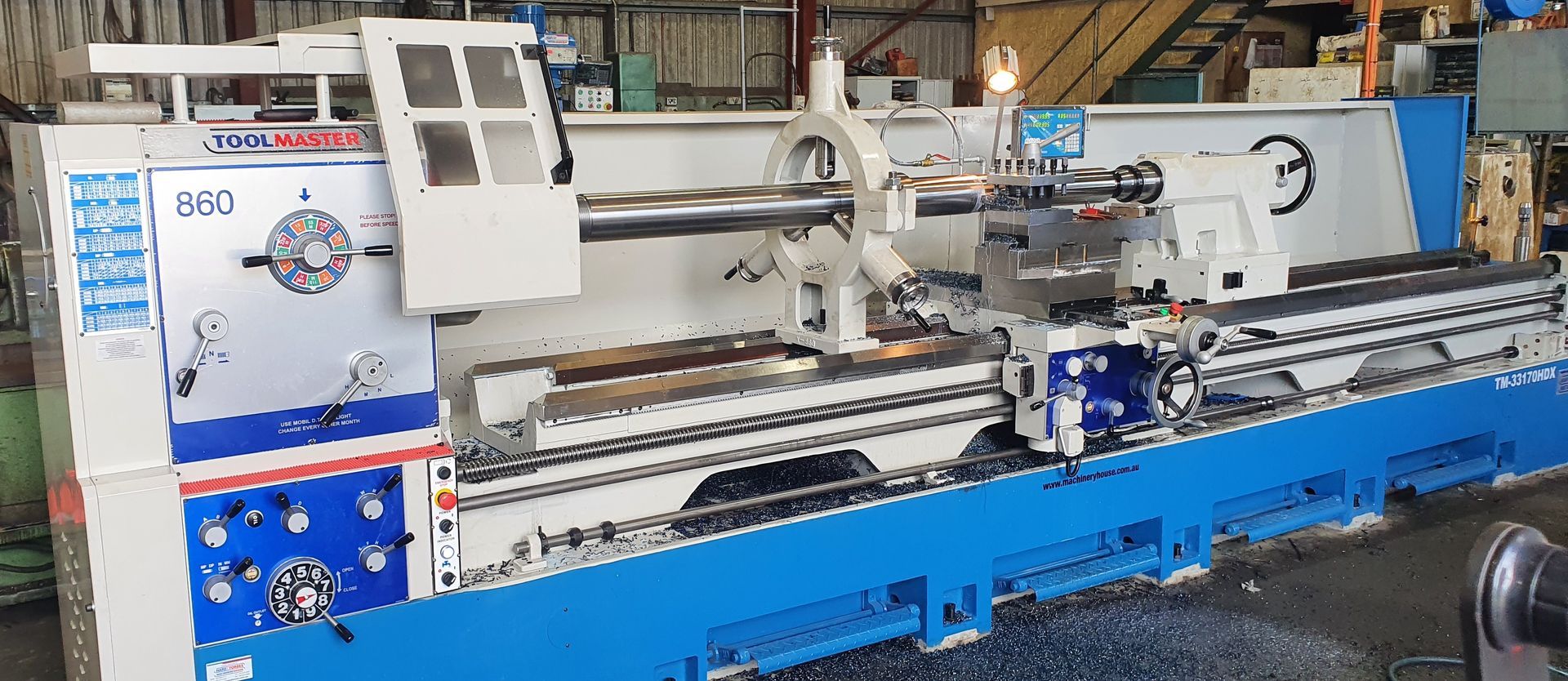 A large blue and white lathe is sitting in a factory.