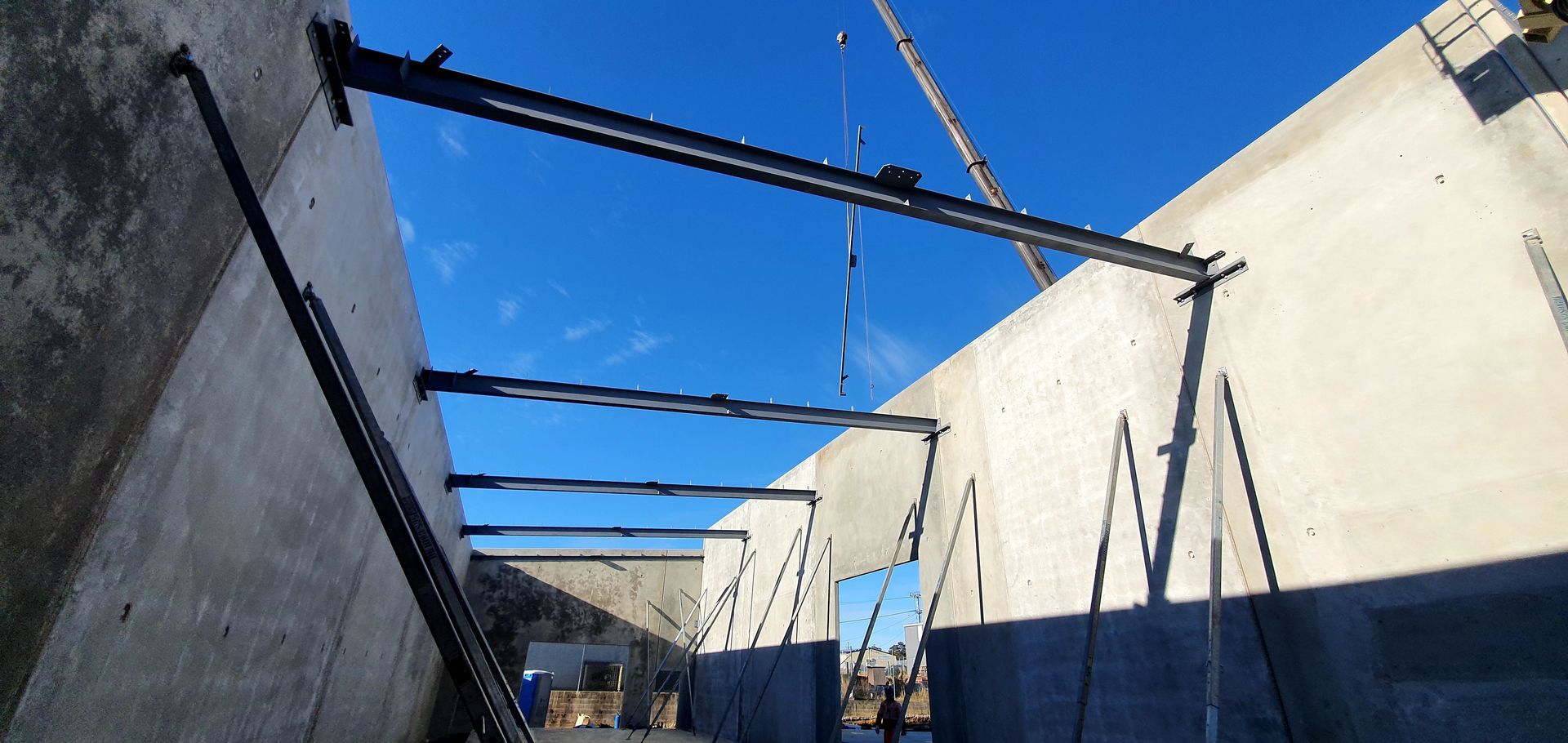 A crane is lifting a concrete wall at a construction site.