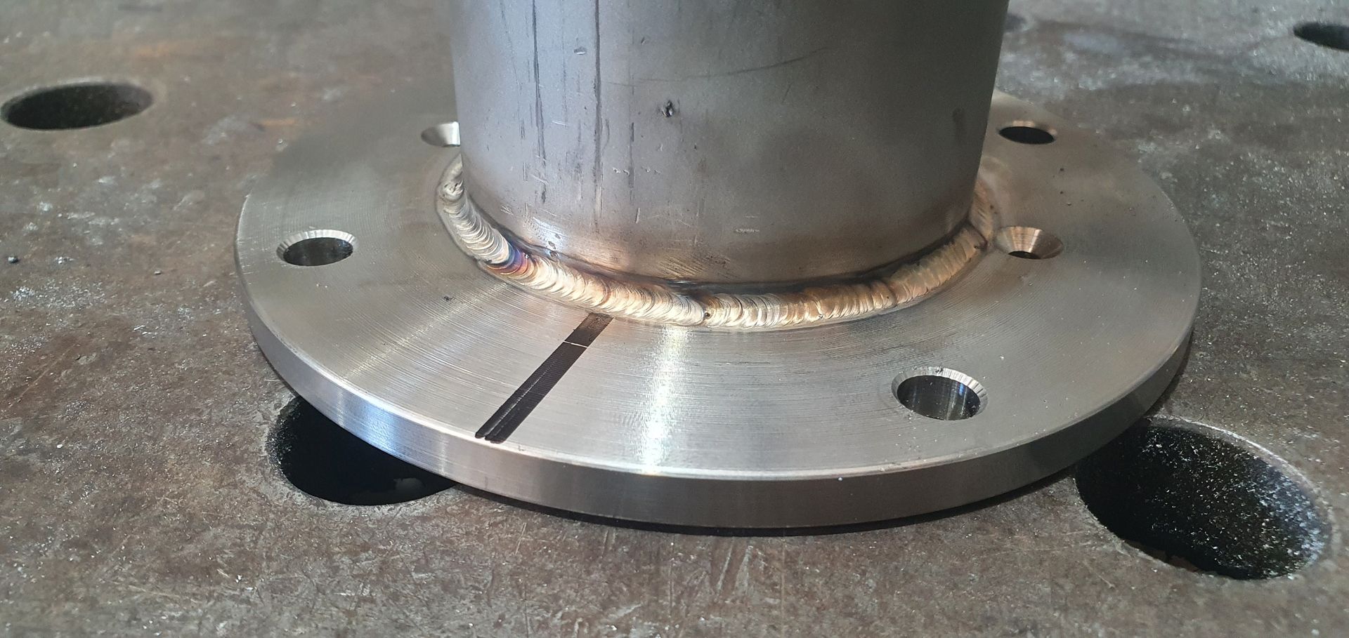 A close up of a metal pipe with a flange on top of it.