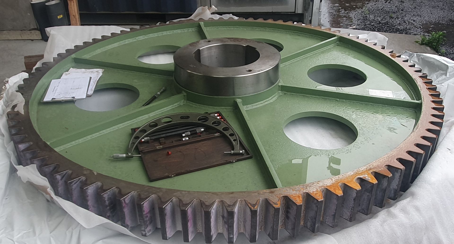 A large green gear is sitting on a white surface.