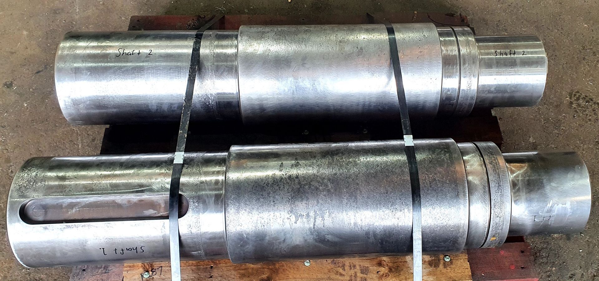Two metal shafts are sitting on top of each other on a wooden table.