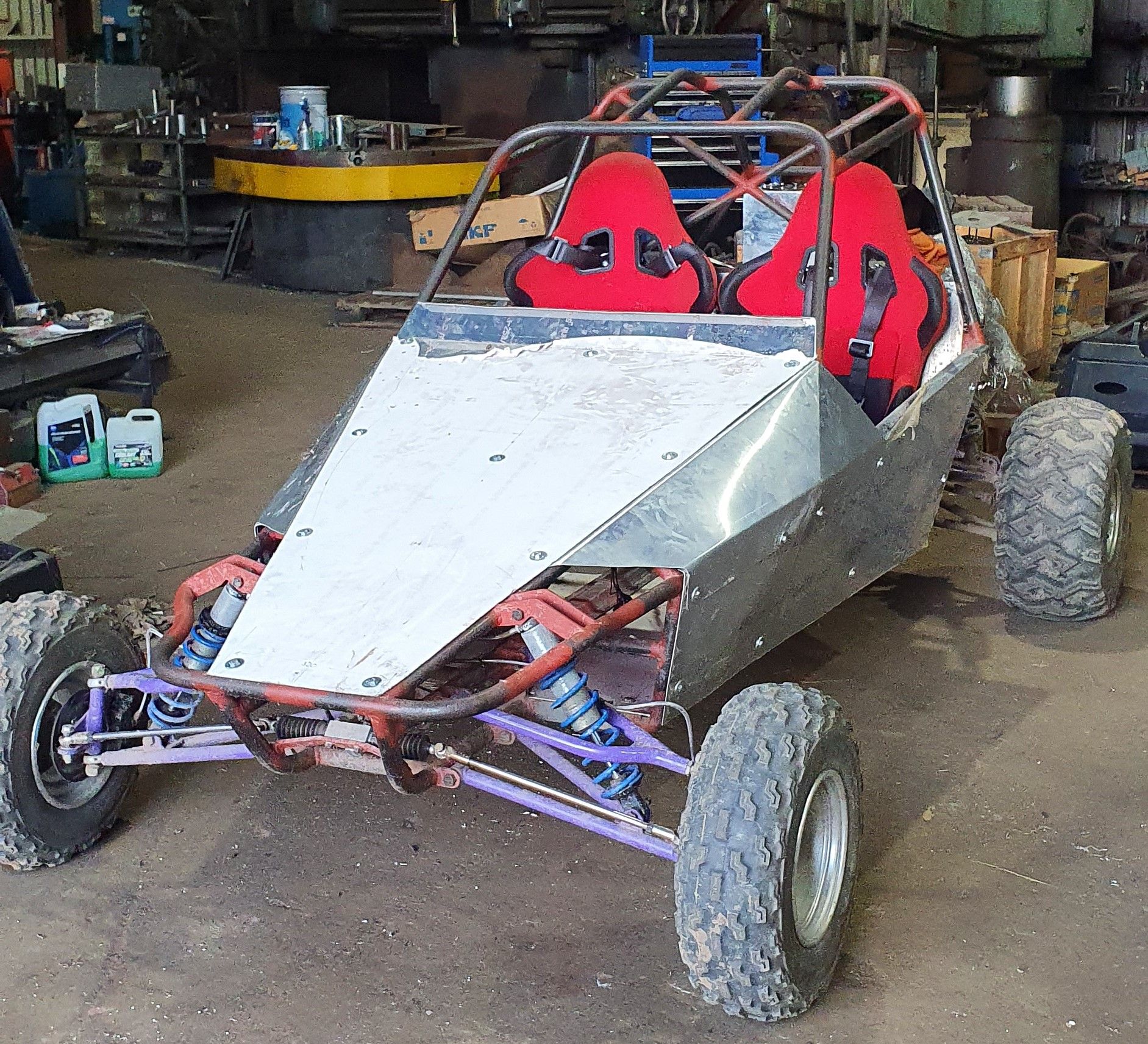 A buggy with red seats is parked in a garage