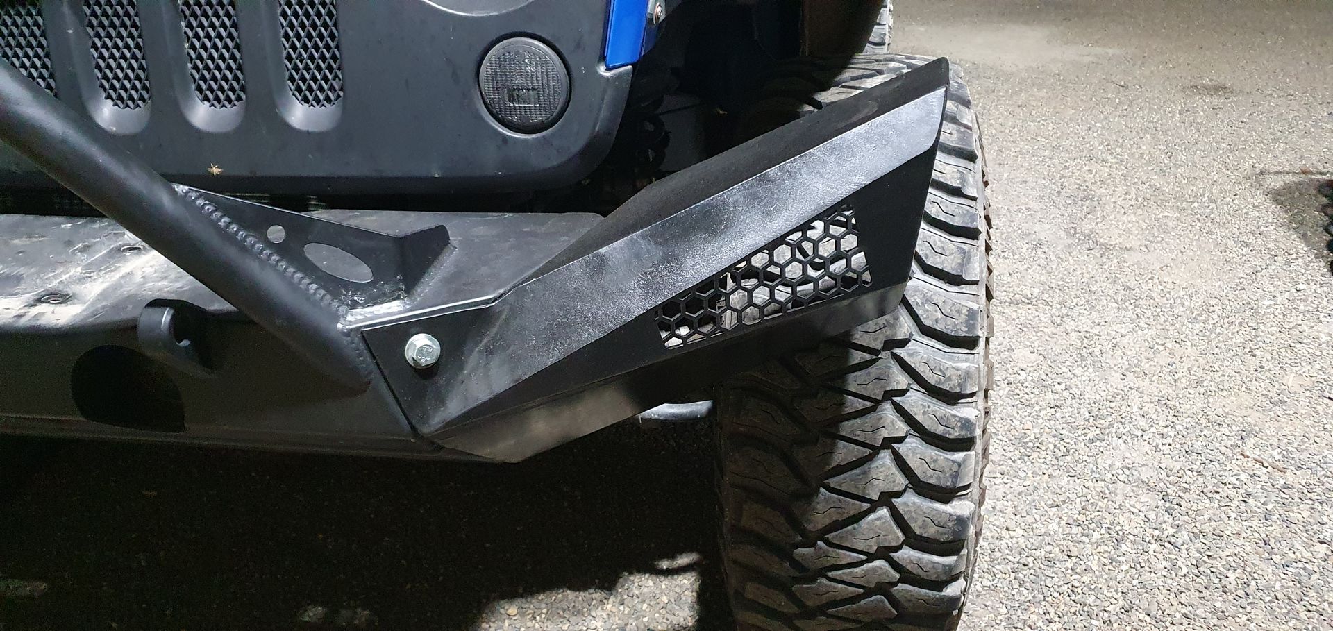 A close up of a jeep 's front bumper and tire.