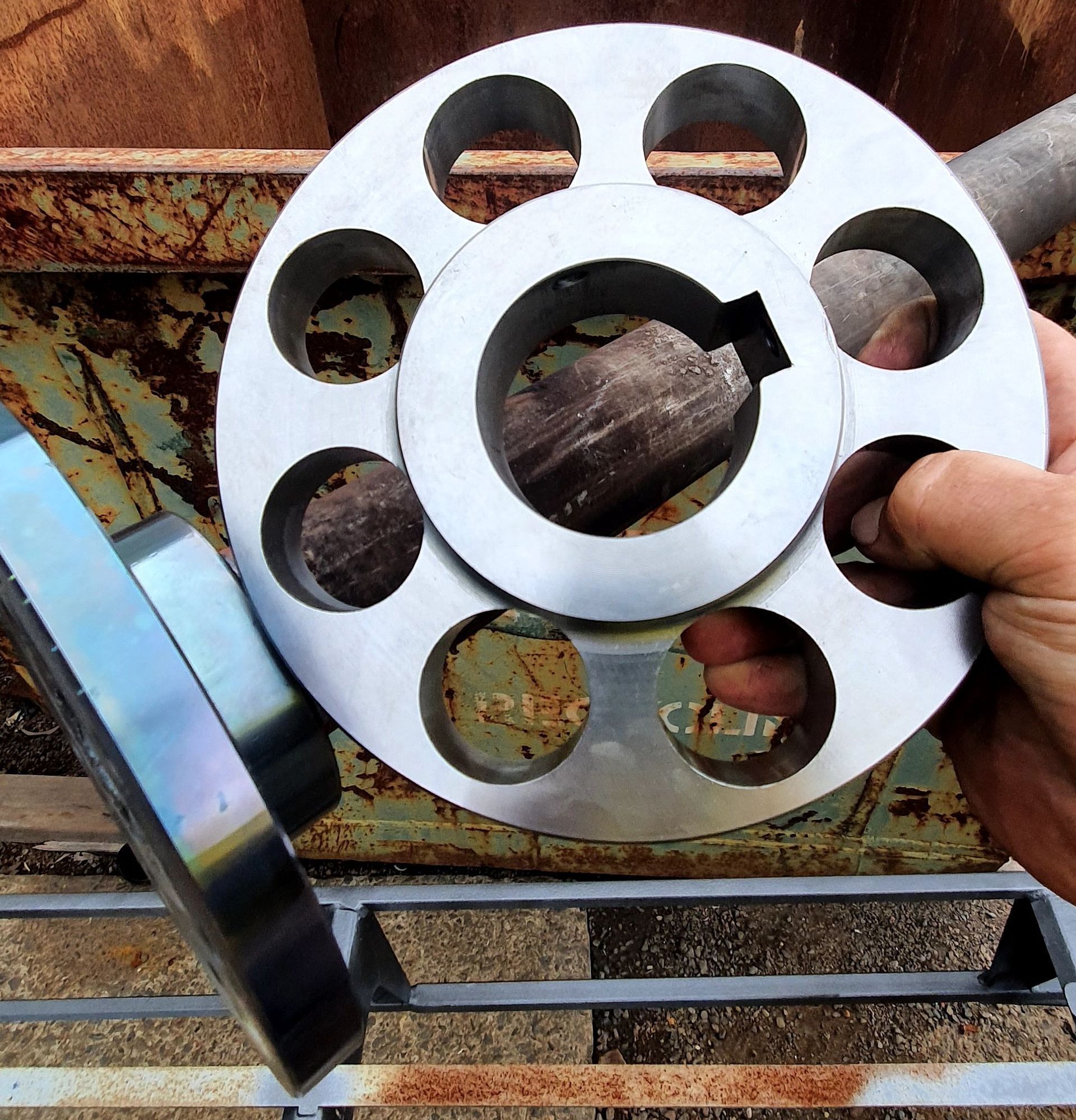 A person is holding a metal disc with holes in it