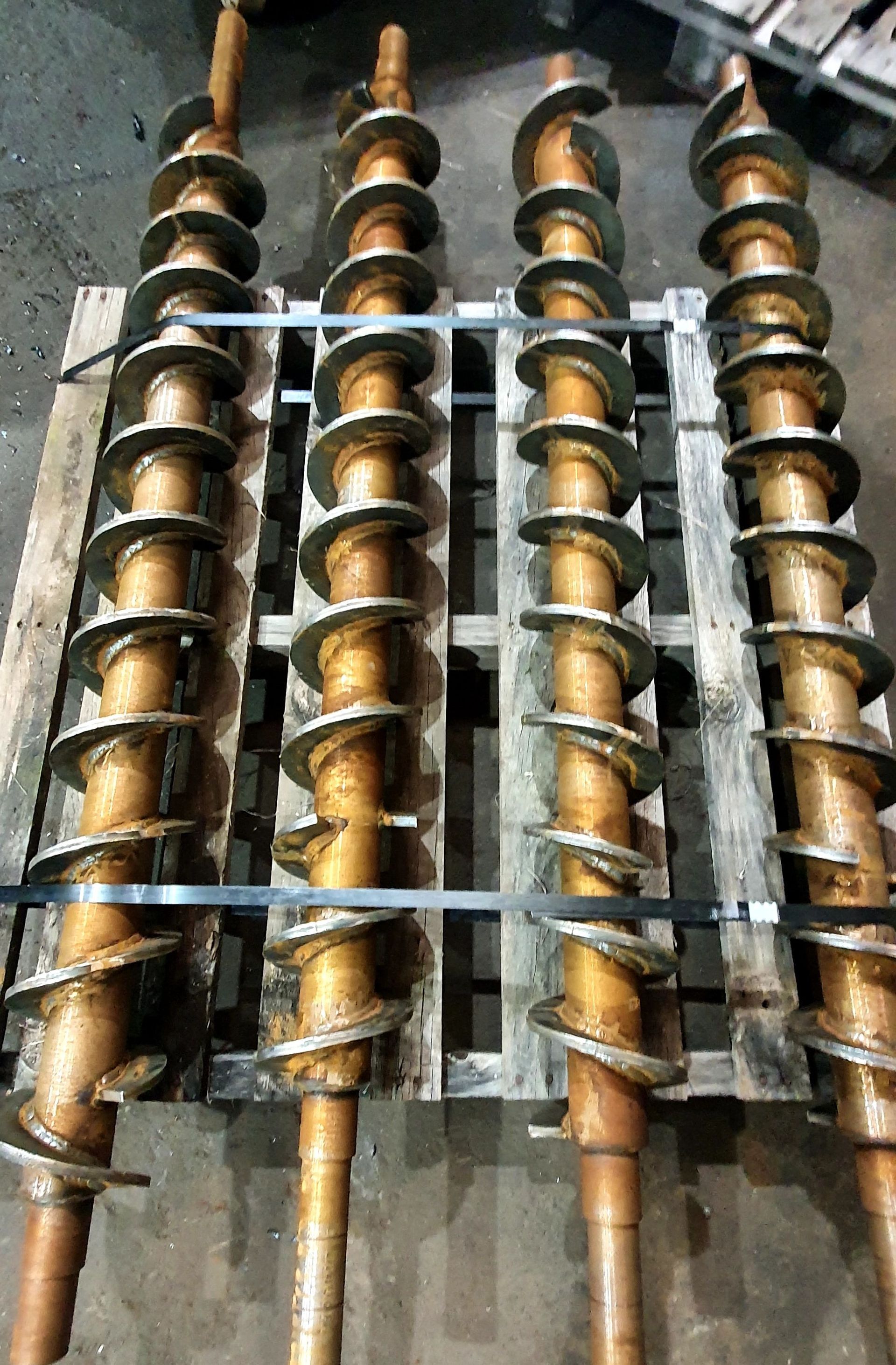 Three metal spirals are stacked on top of each other on a wooden pallet.