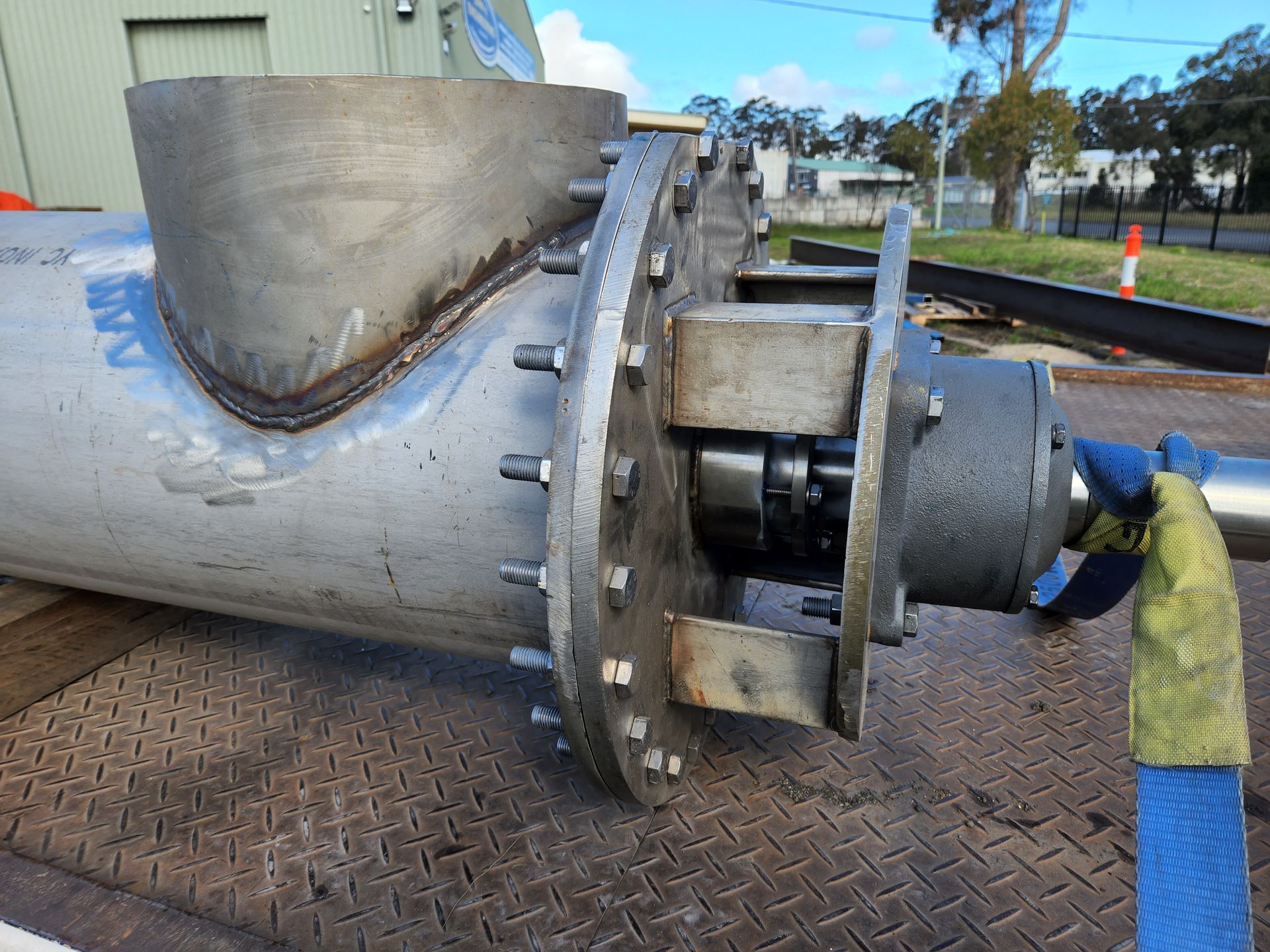 A large stainless steel pipe is sitting on a metal surface.