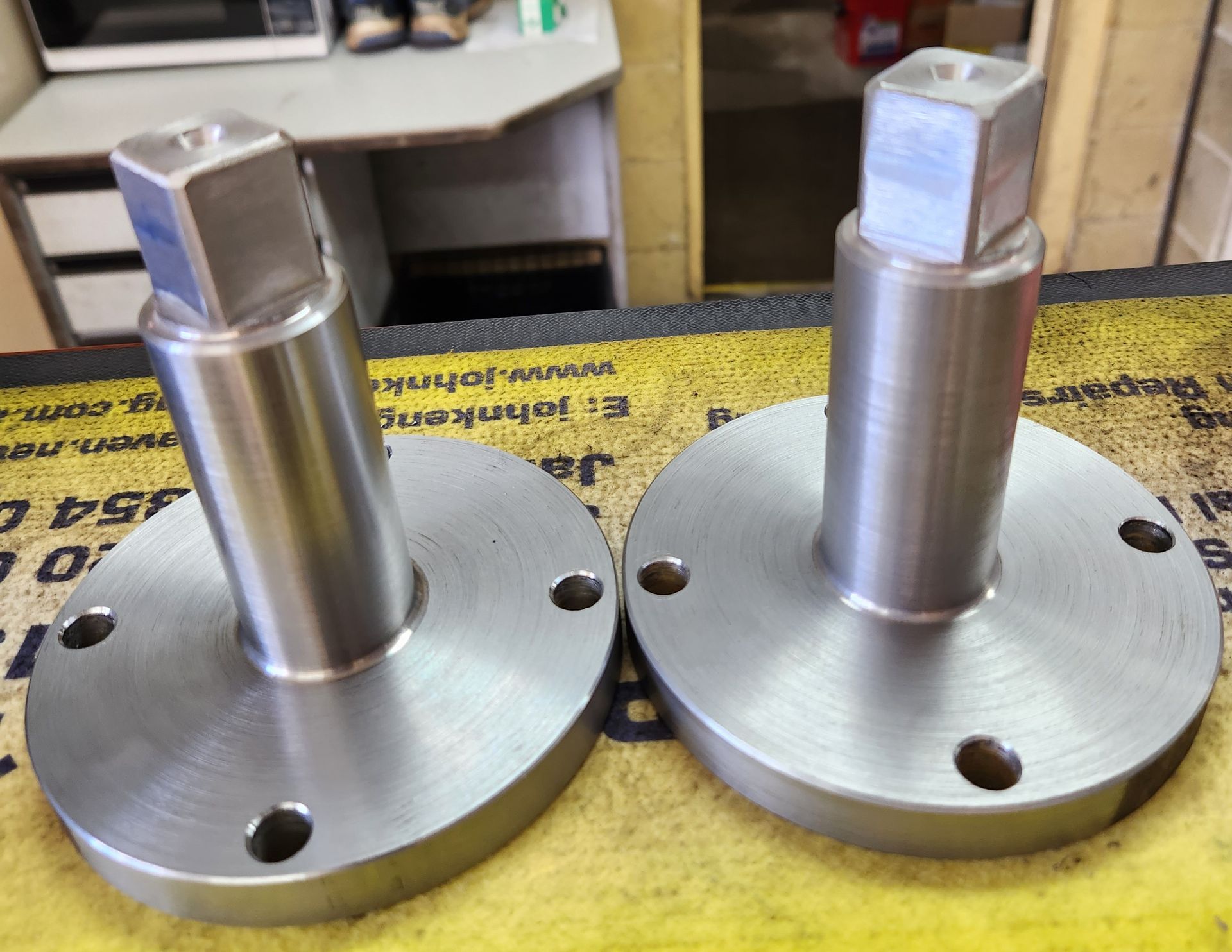 Two stainless steel pieces are sitting on a yellow mat