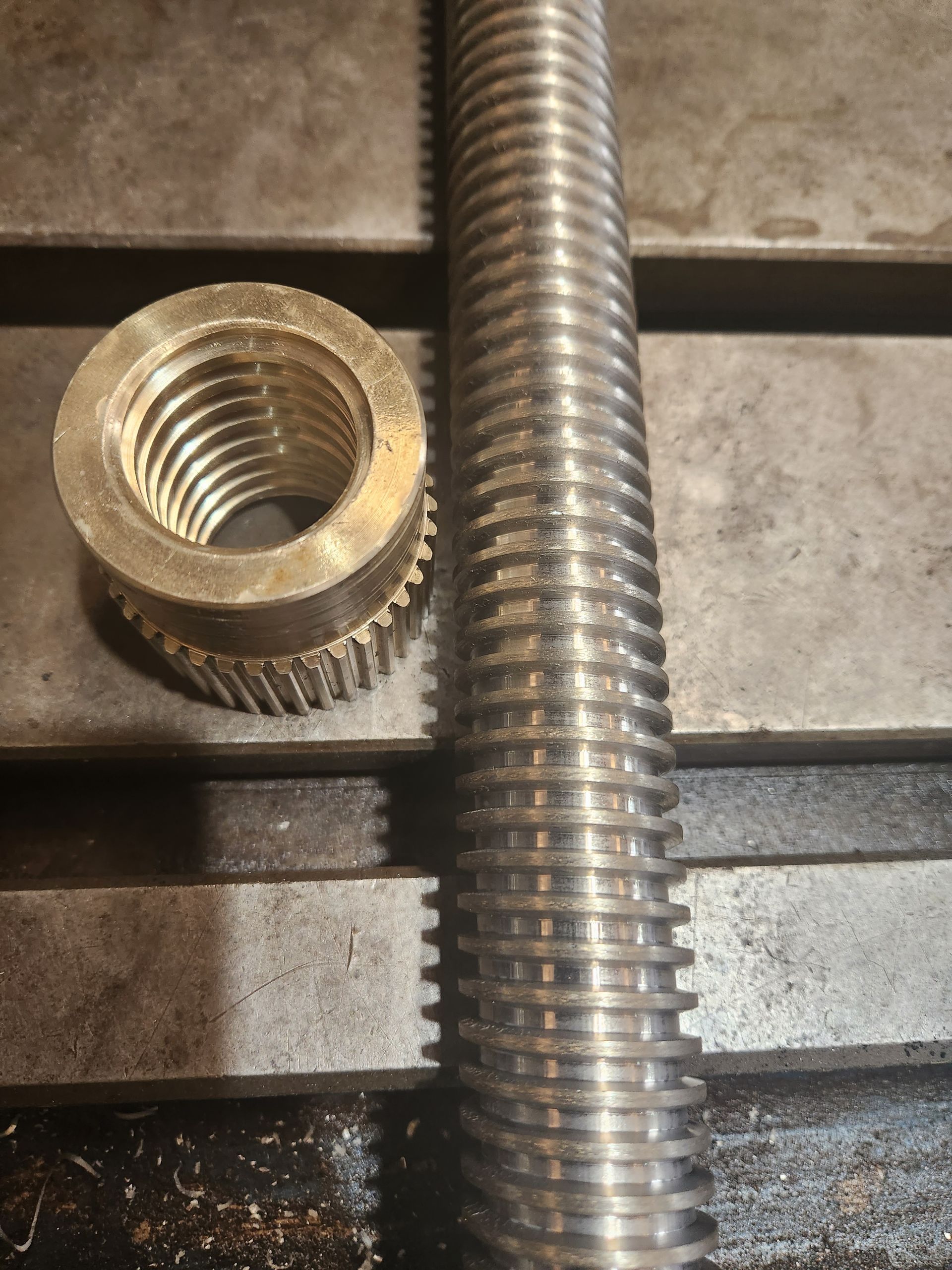 A nut is sitting next to a metal rod on a table.