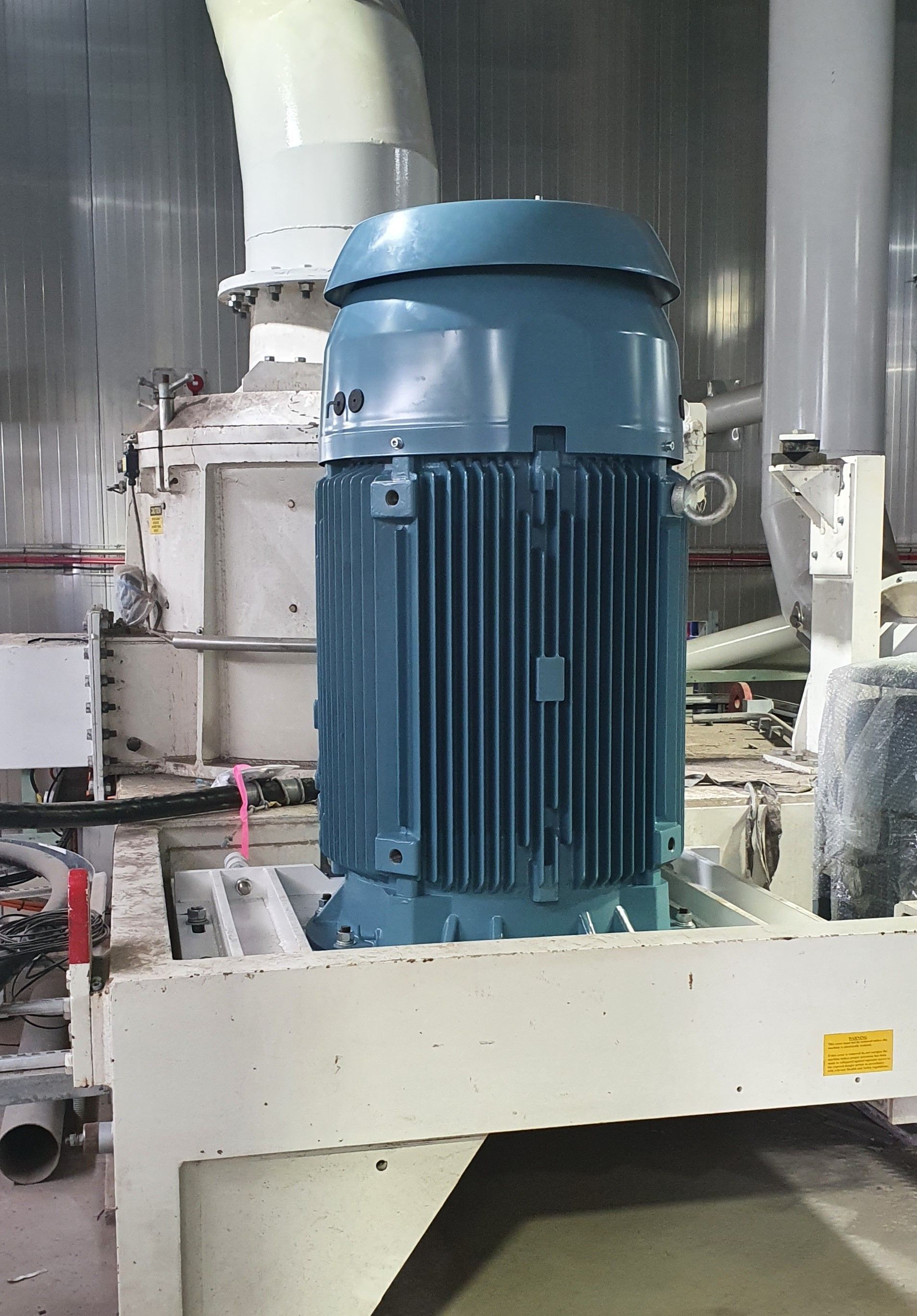 A large blue electric motor is sitting on top of a machine.