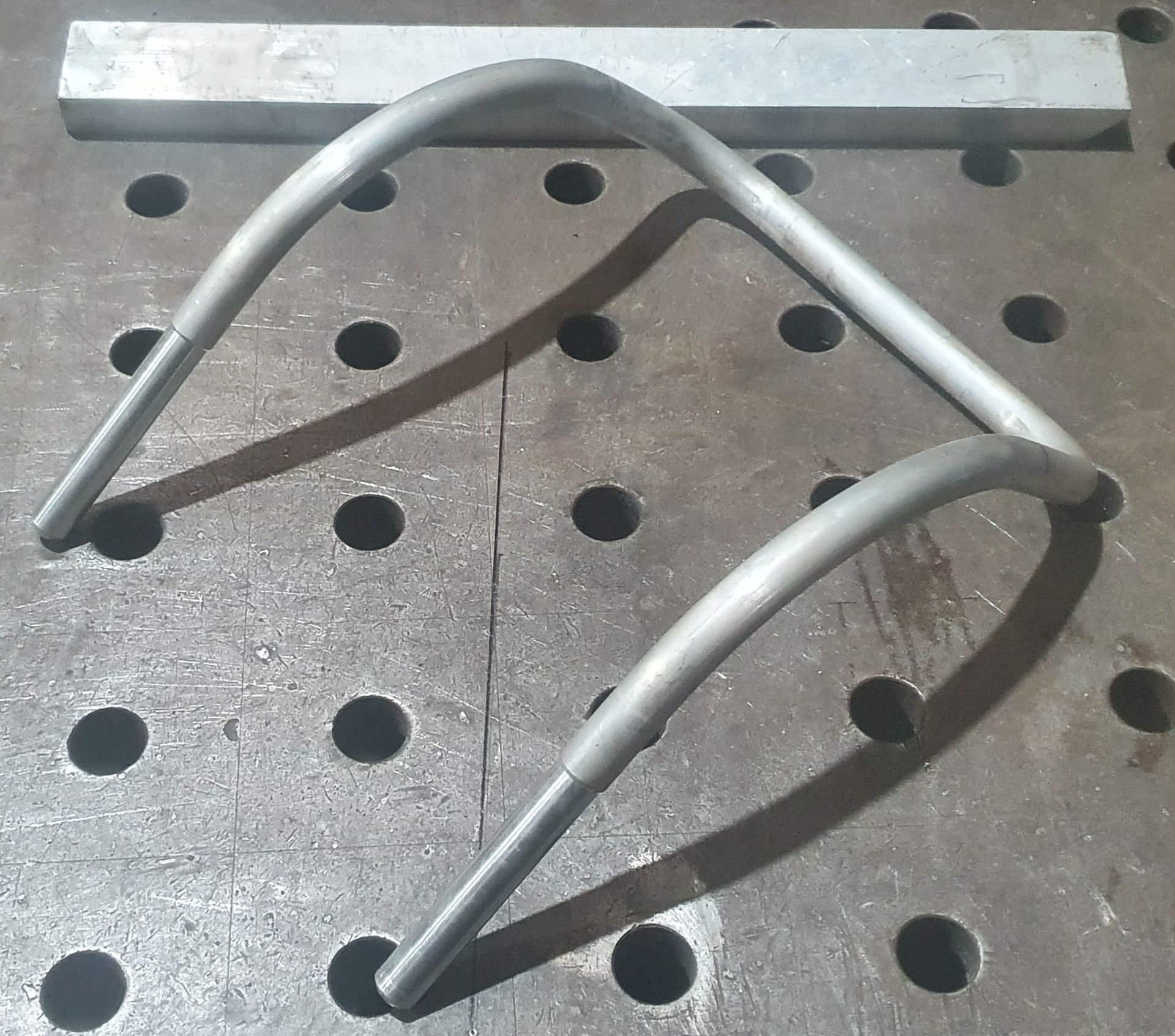 A piece of metal is sitting on a table with holes in it
