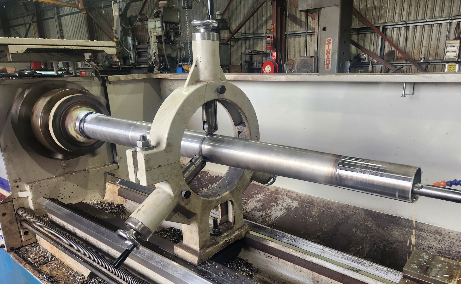 A lathe is cutting a piece of metal in a factory.
