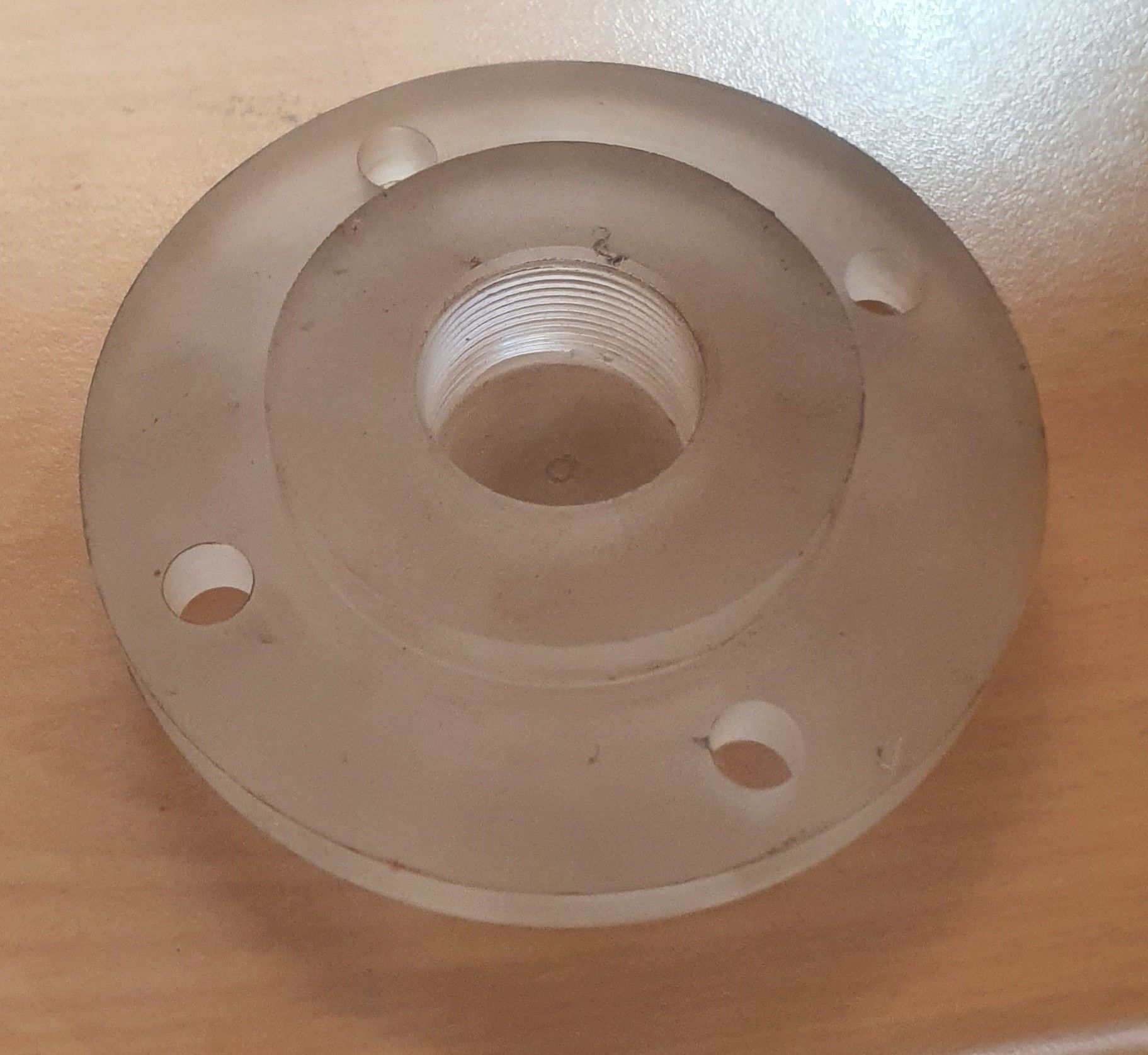 A clear plastic ring with holes in it is sitting on a wooden table.