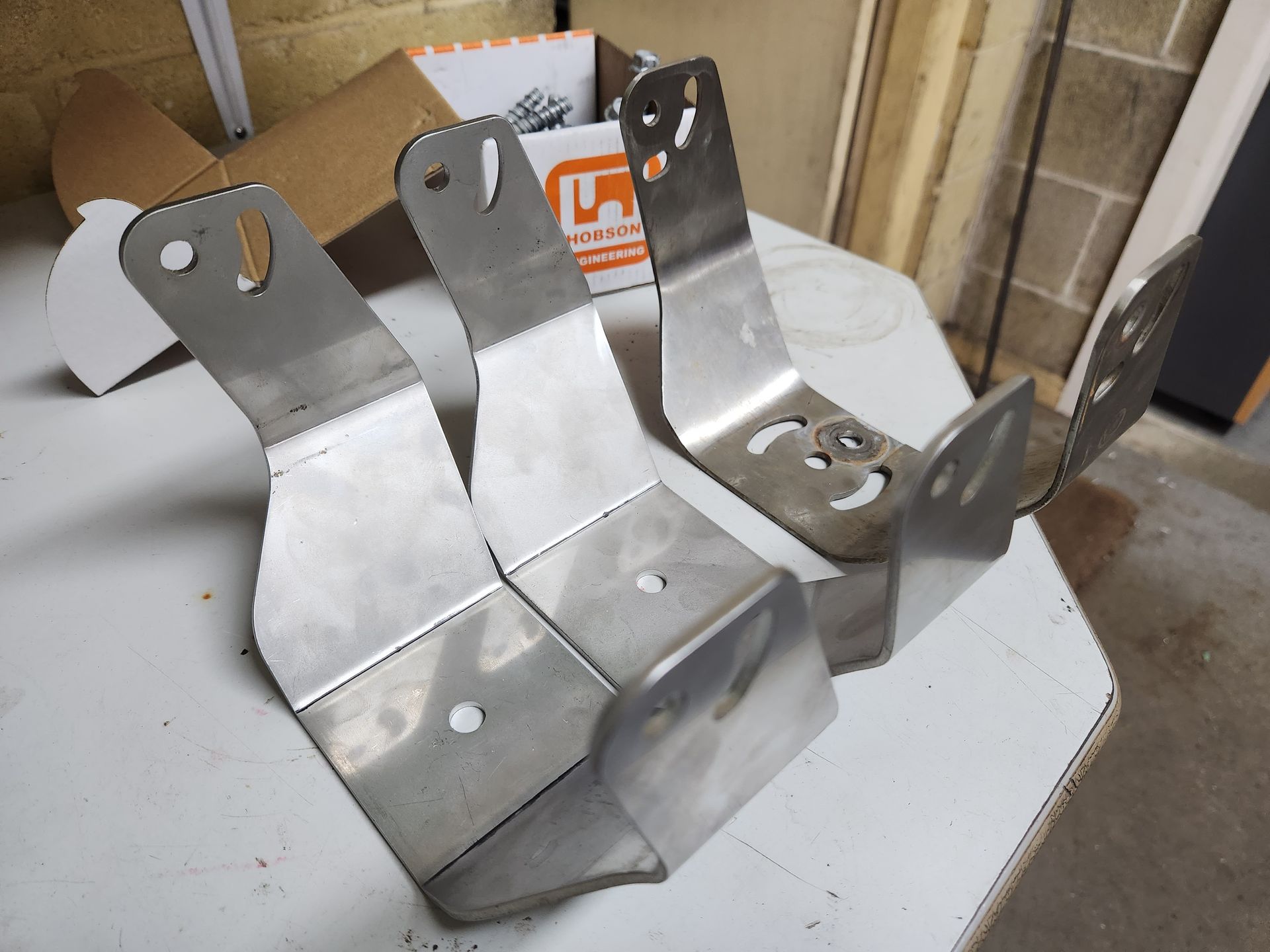 A pair of stainless steel brackets are sitting on a white table