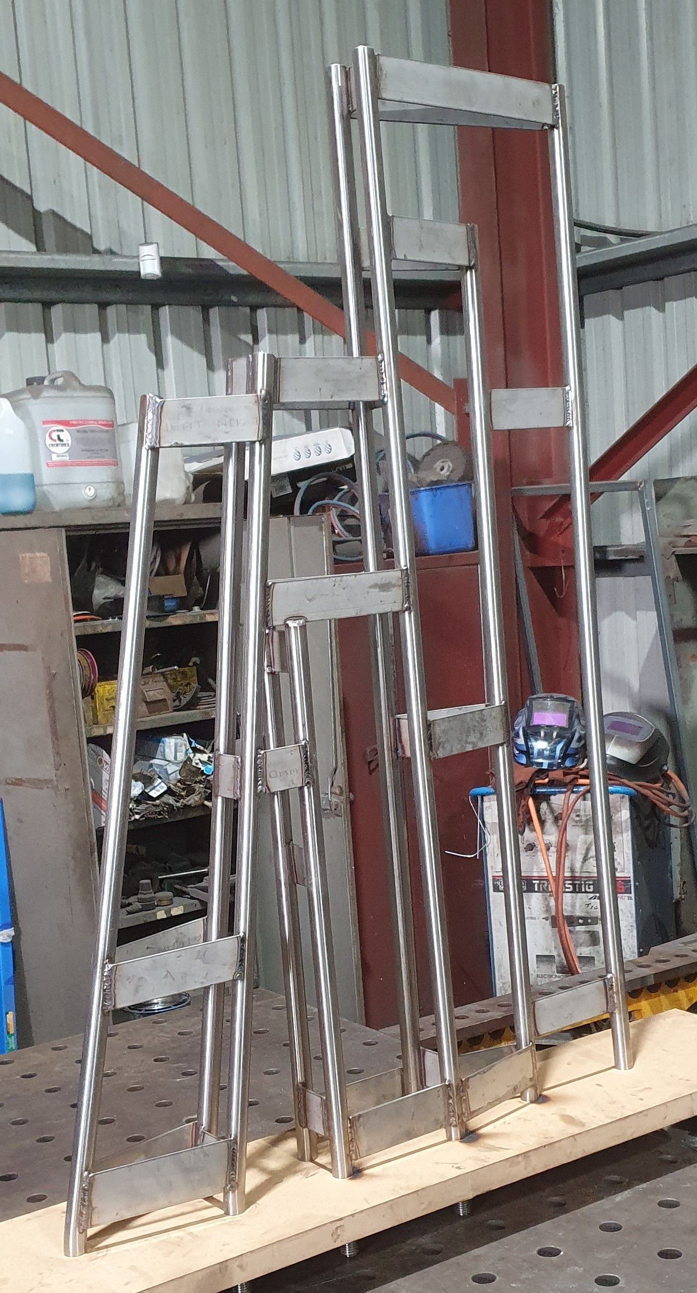 A row of stainless steel ladders sitting on top of a wooden table.