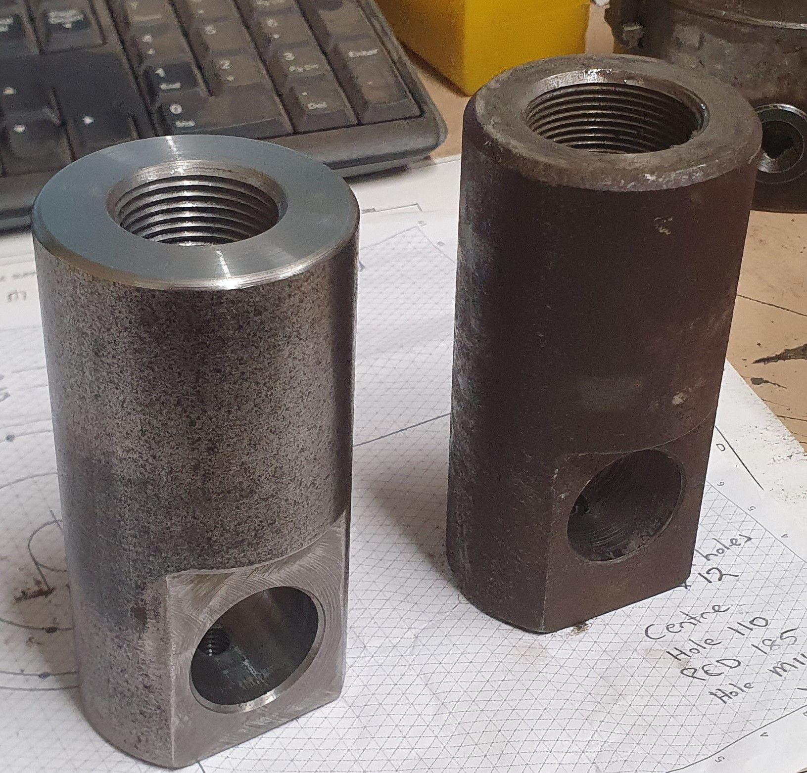 Two metal cylinders with holes in them are sitting on a piece of paper next to a keyboard