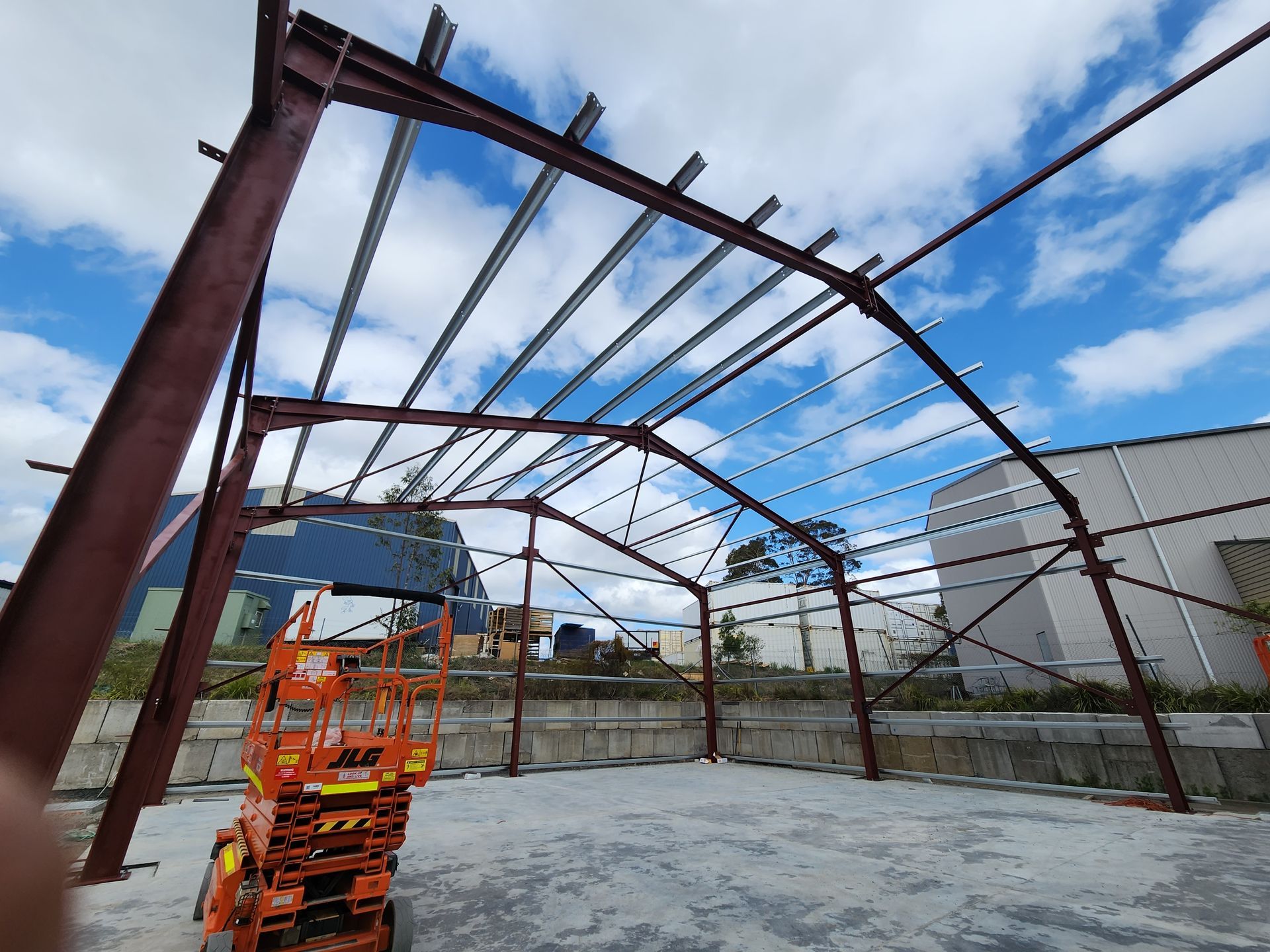 A large metal structure is being built in a parking lot.