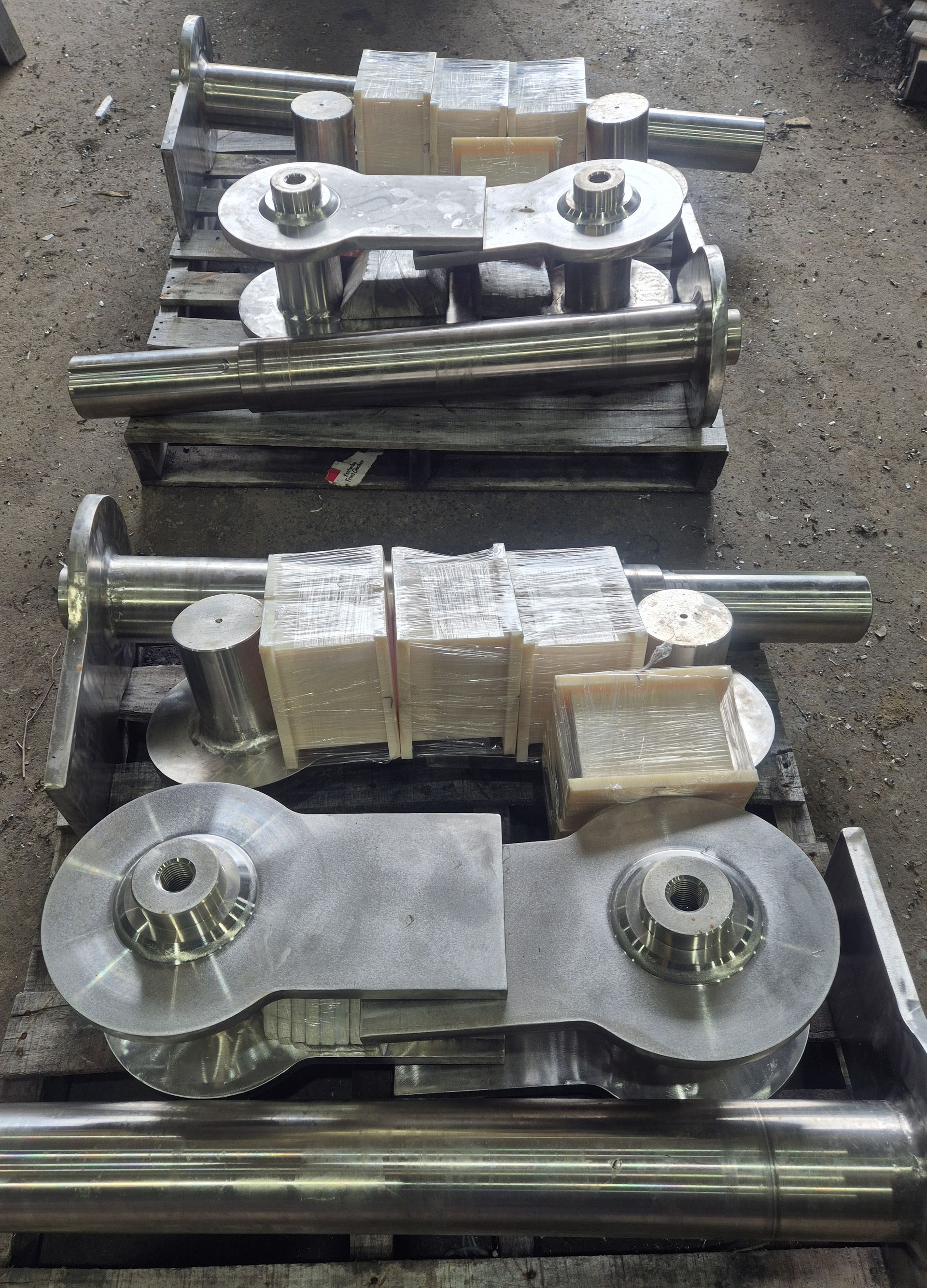 A bunch of metal parts are sitting on top of each other on a wooden pallet.