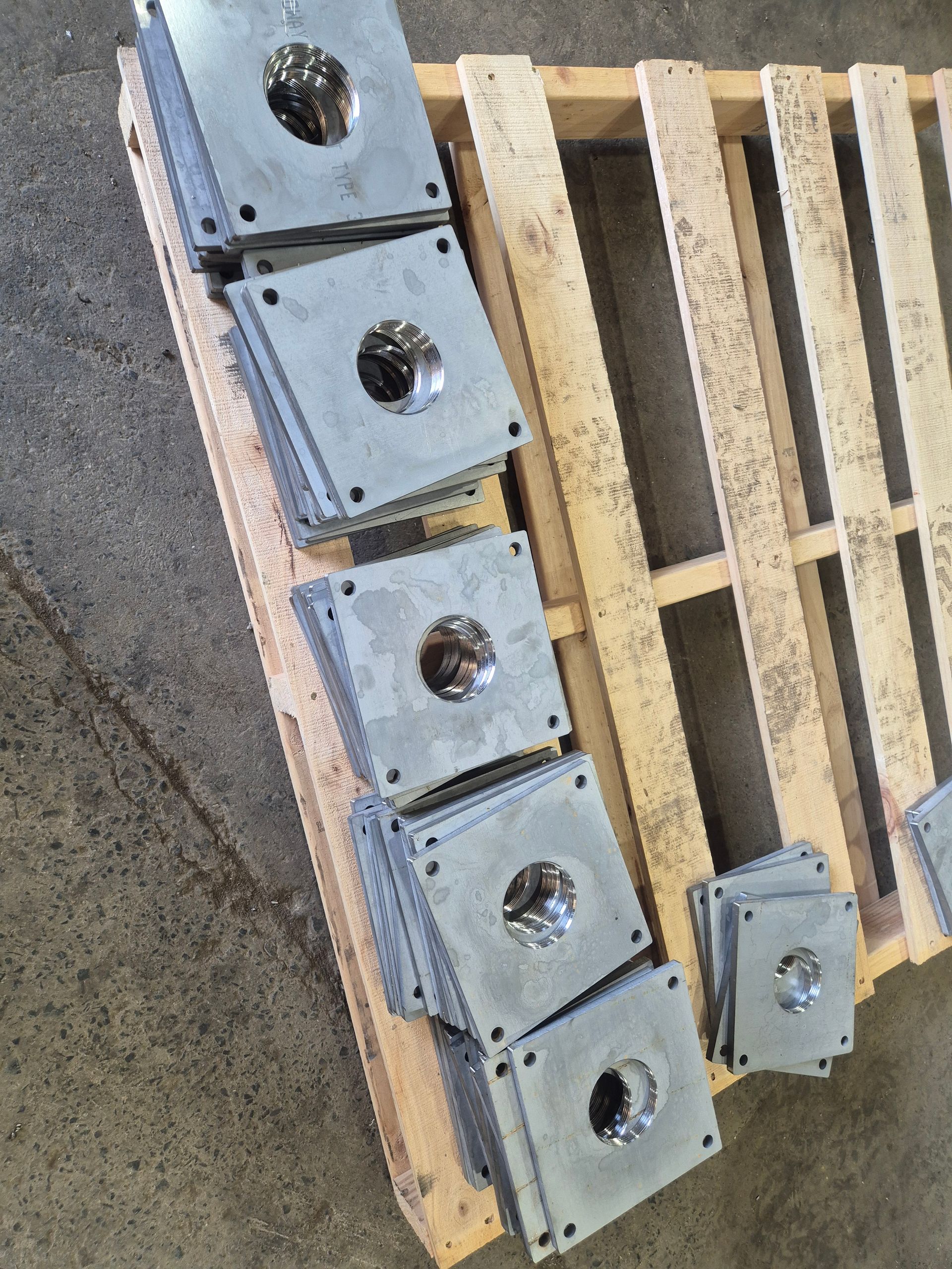 A wooden pallet with a bunch of metal pieces on it