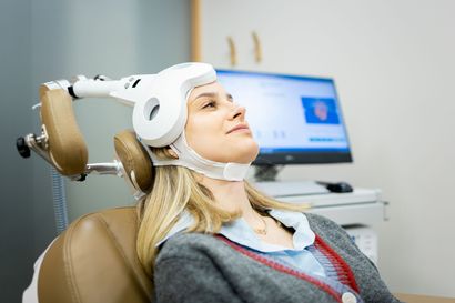 Woman in a dental chair wearing a head brace, with a monitor in the background