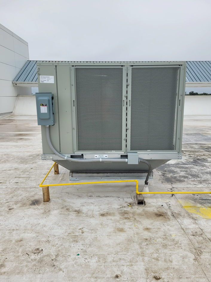 Rooftop HVAC unit with gray vents and a blue electrical box on a concrete roof.