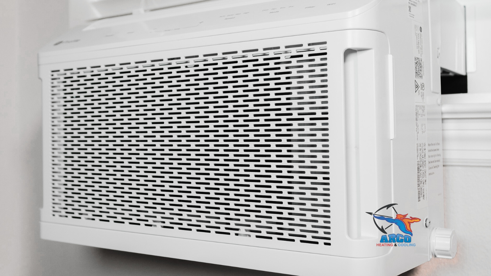 A white air conditioner is hanging on a wall next to a window.