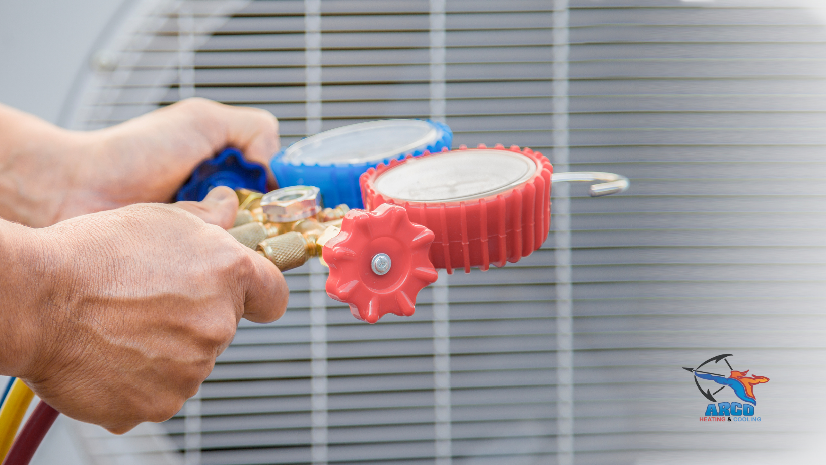 Hands holding a gauge manifold near an air conditioner unit.