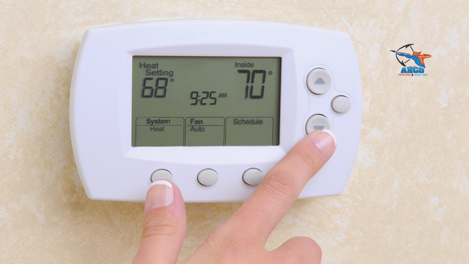 Hand adjusting a digital thermostat on a wall, setting the desired temperature.