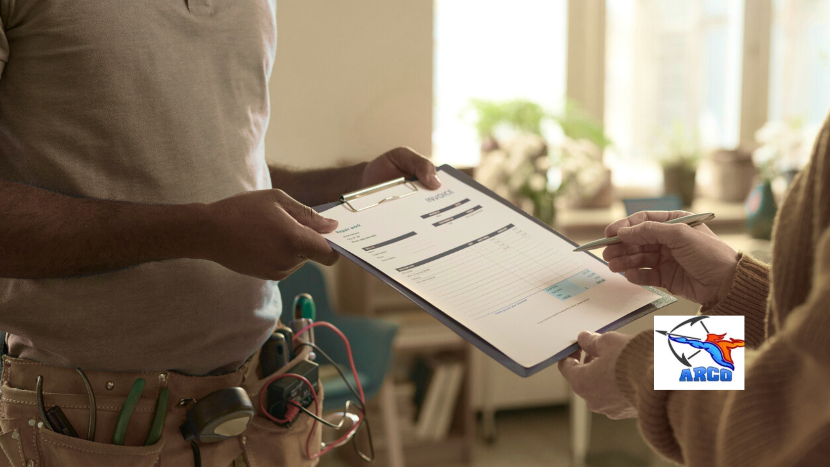 A person in a tool belt hands a clipboard to another person who is signing a ARCO document indoors.