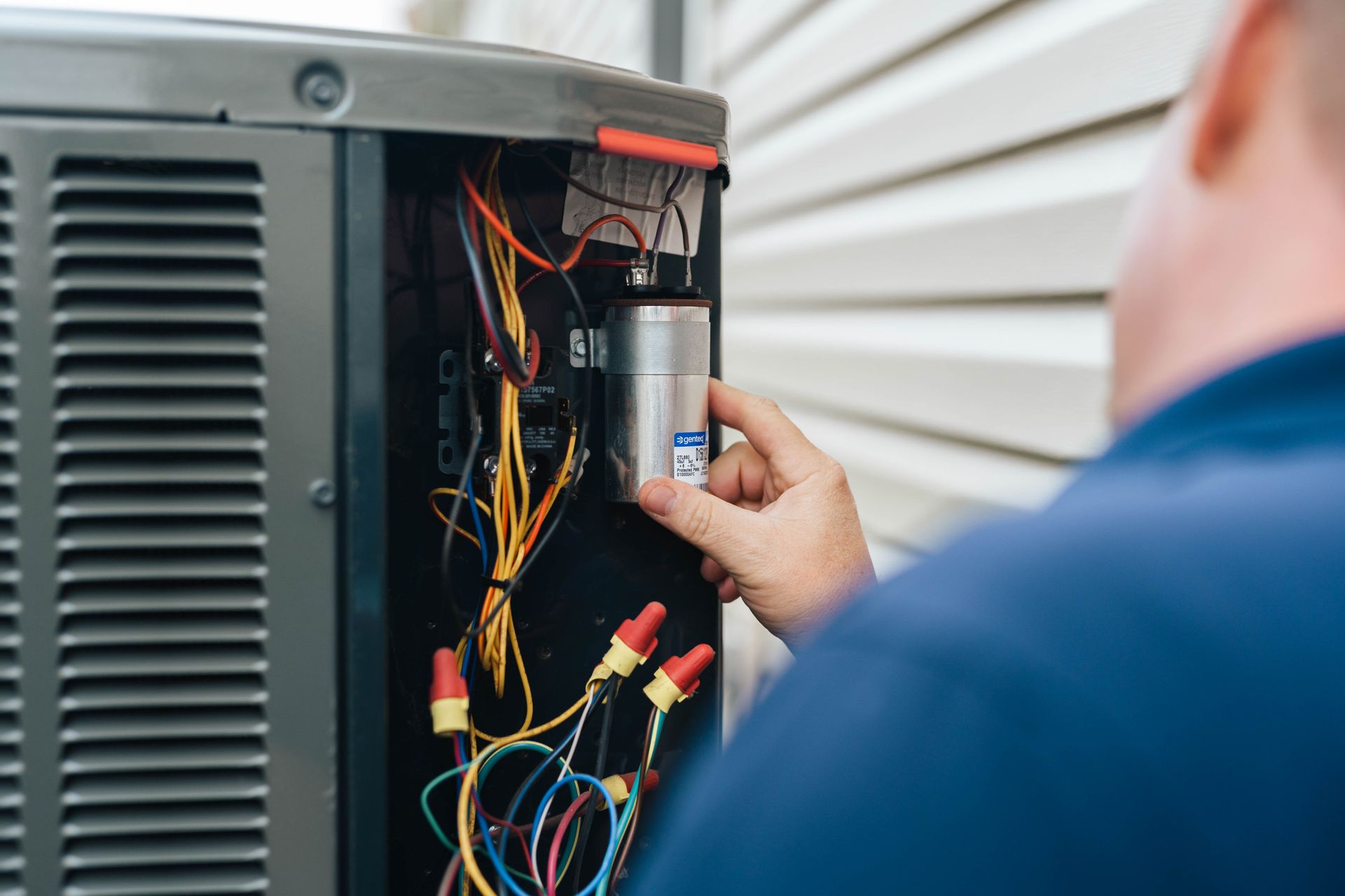 a man working on an outside air conditioner