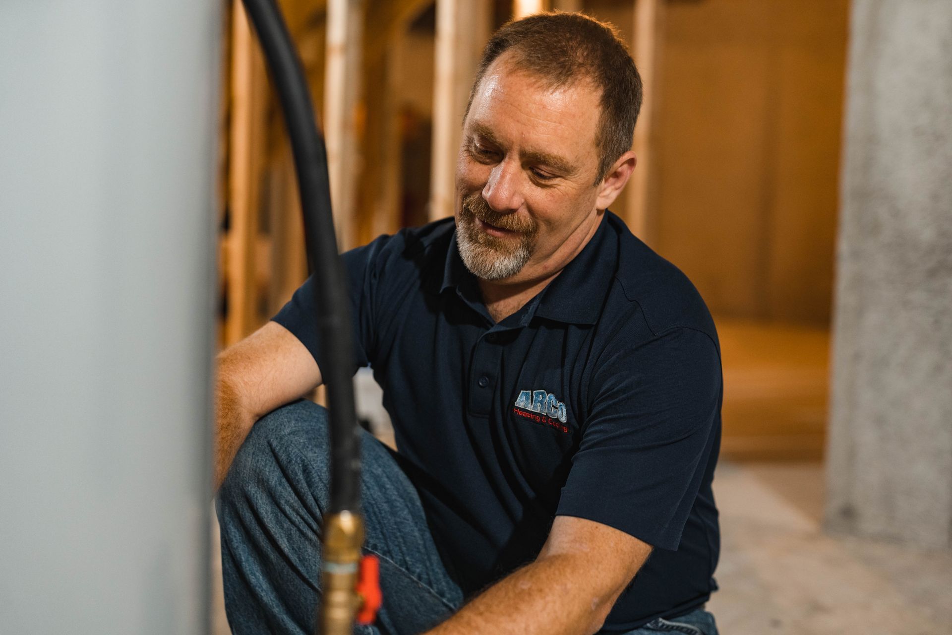 A man is sitting on the floor fixing a water heater.