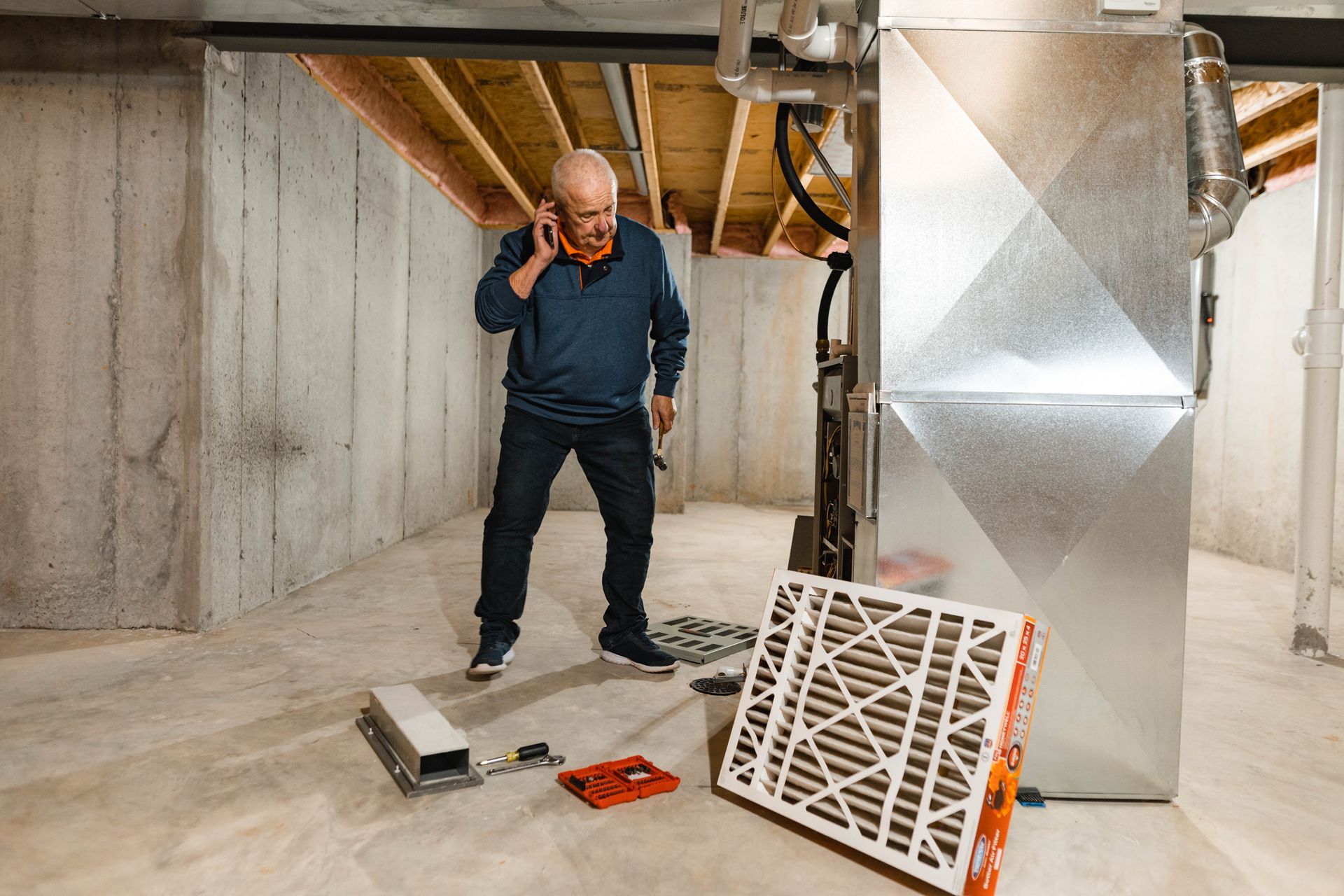 A man is standing in a basement talking on a cell phone.