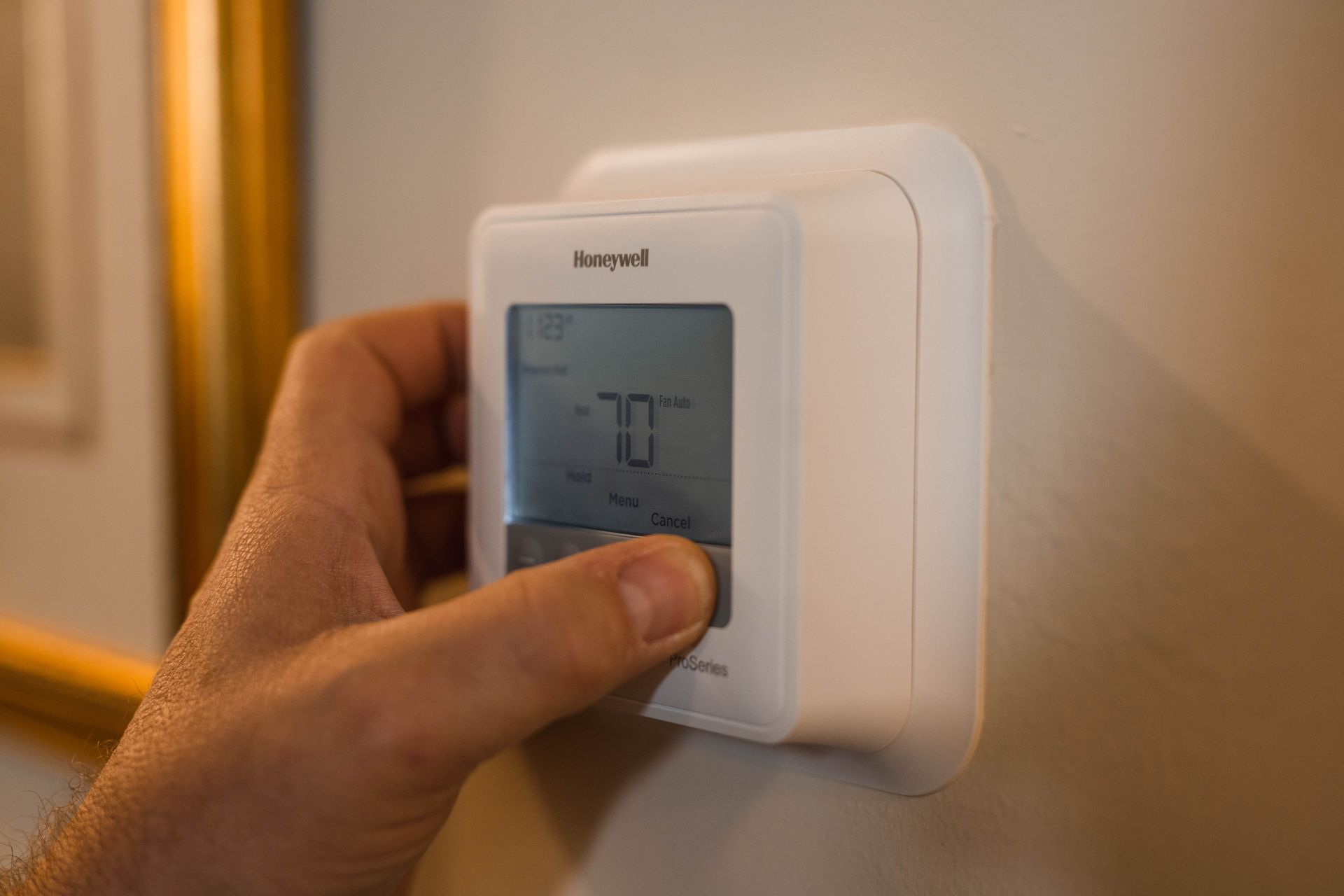 A person is adjusting a thermostat on a wall.