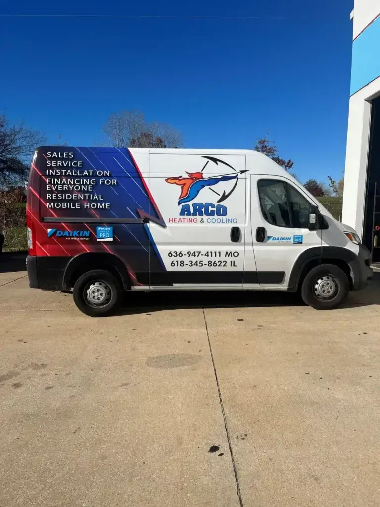 A red , white and blue van is parked in front of a building.