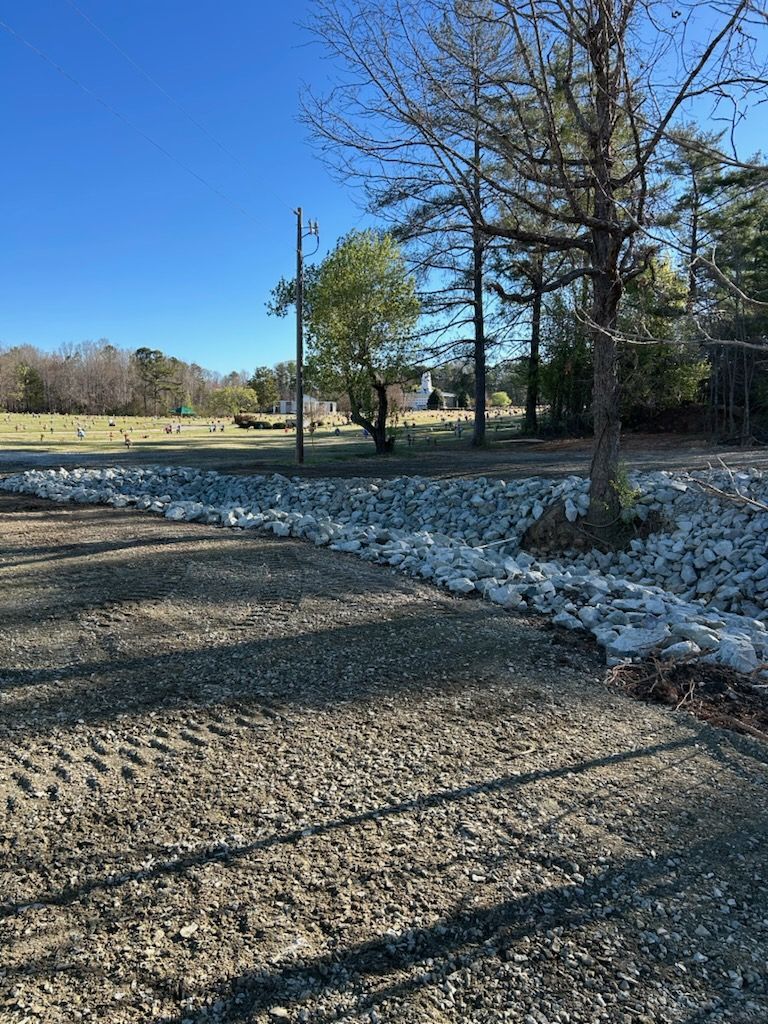 Gravel path beside a snowy wooded field under a clear blue sky