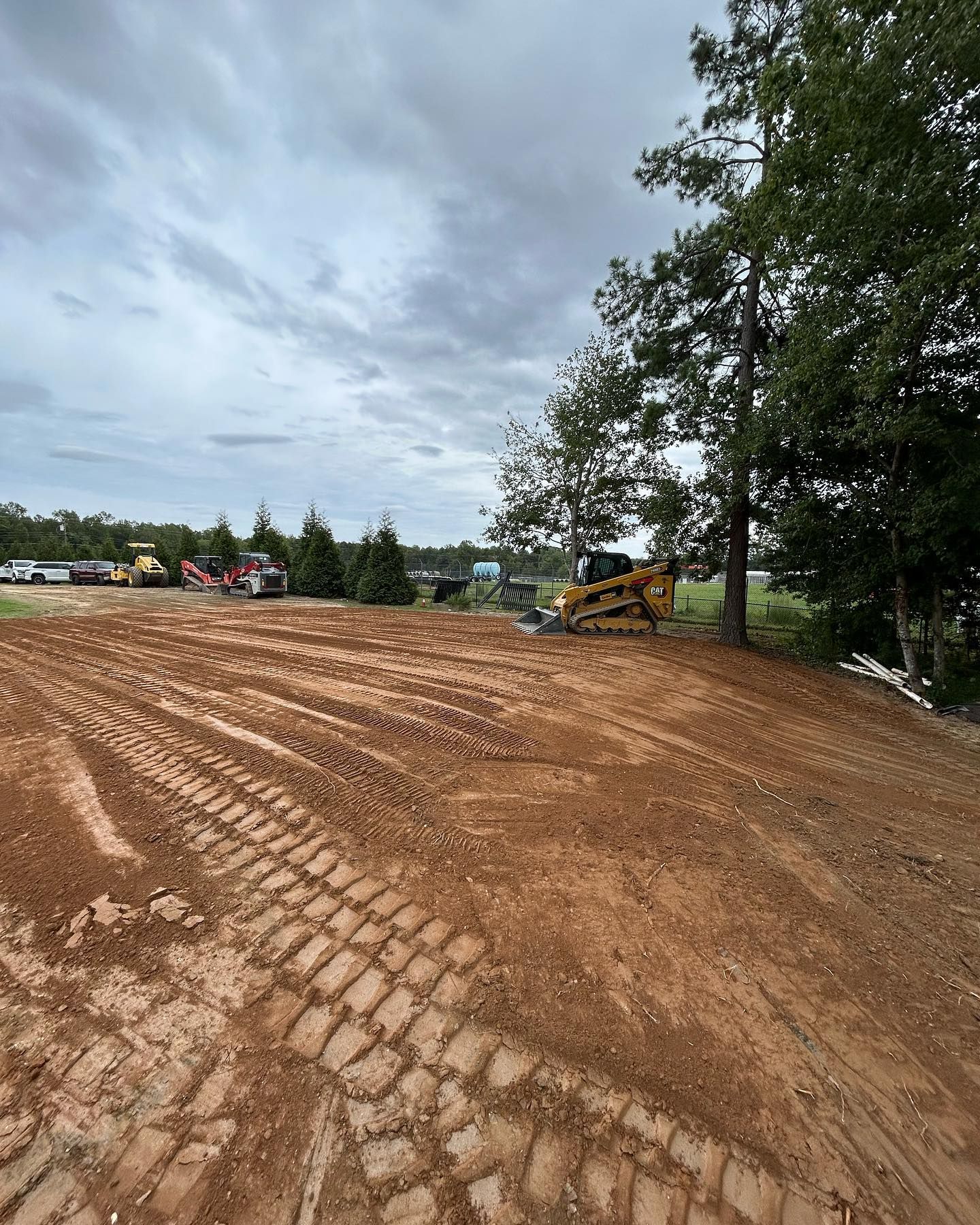 Construction site with excavator on a dirt slope under cloudy sky