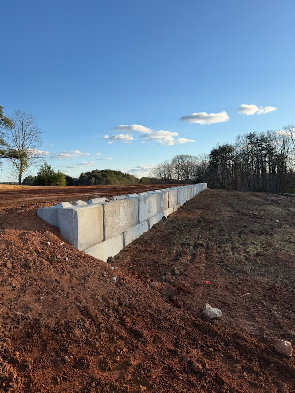 Concrete retaining wall blocks along a dirt embankment under a clear blue sky
